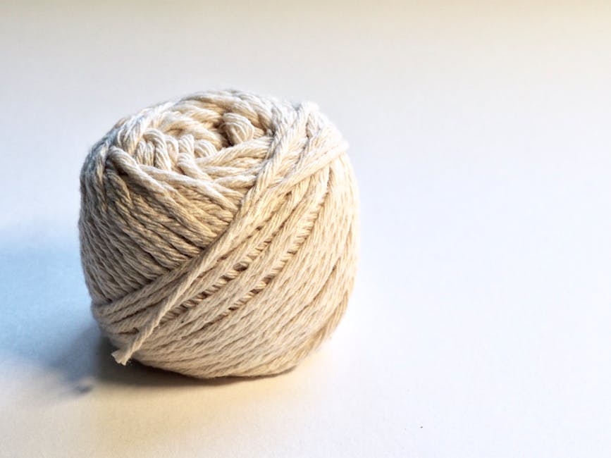 Detailed close-up of a natural cotton yarn ball on a white background, perfect for textile and crafting themes.